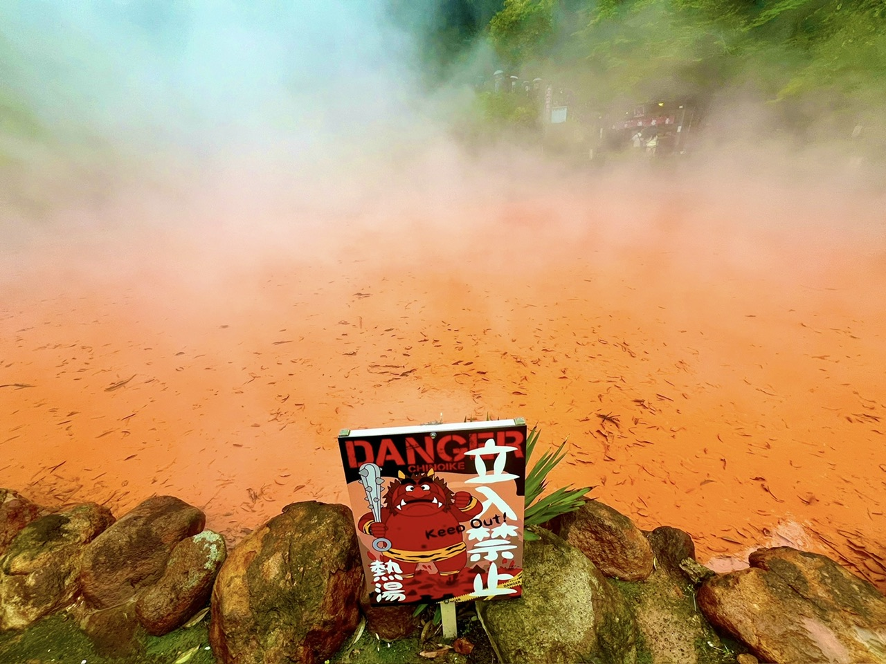 a view of red mud hot spring with a danger warning sign