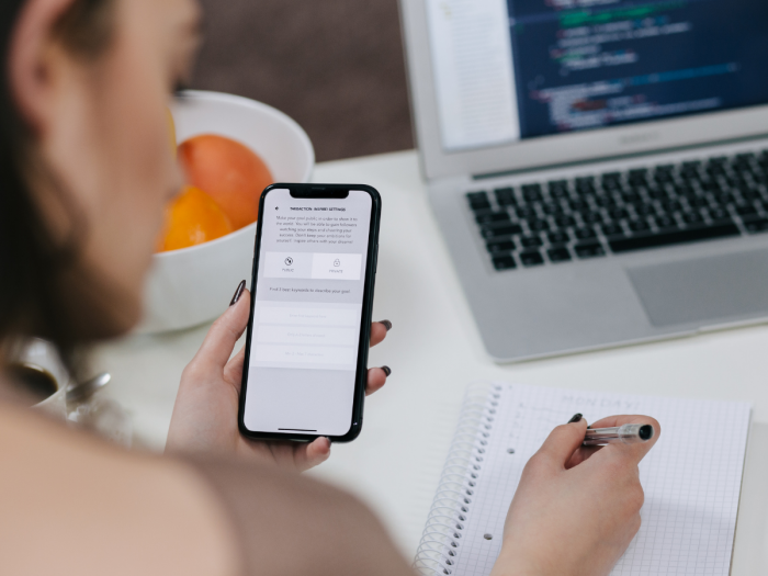 Person using smartphone while taking notes at desk