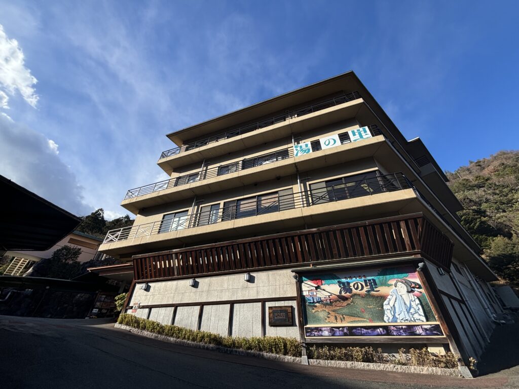 Multi-story Japanese hotel or ryokan building with traditional architectural elements and decorative mural