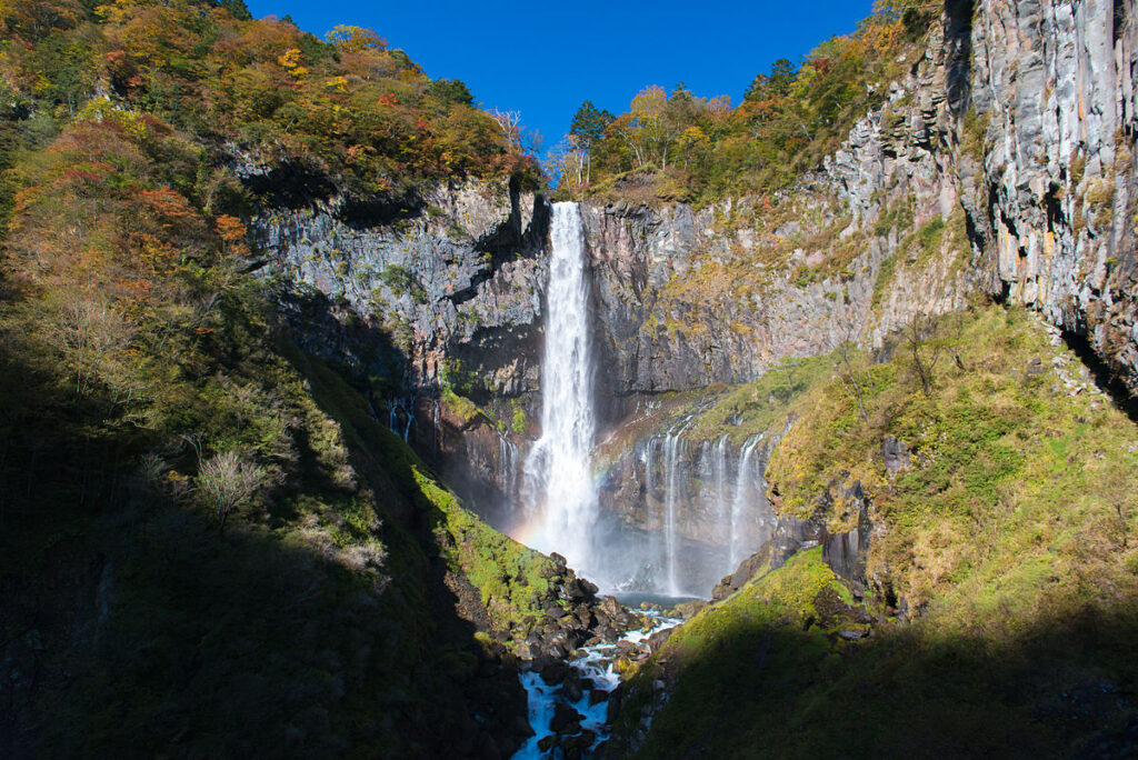 Kegon Waterfall Nikko Japan natural landmark surrounded by autumn colored cliffs and forest under blue sky