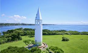 ighthouse-like white tower standing on a green hilltop overlooking the ocean