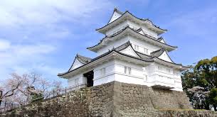 Traditional Japanese castle tower (tenshu) with white walls and layered roofs on stone foundation