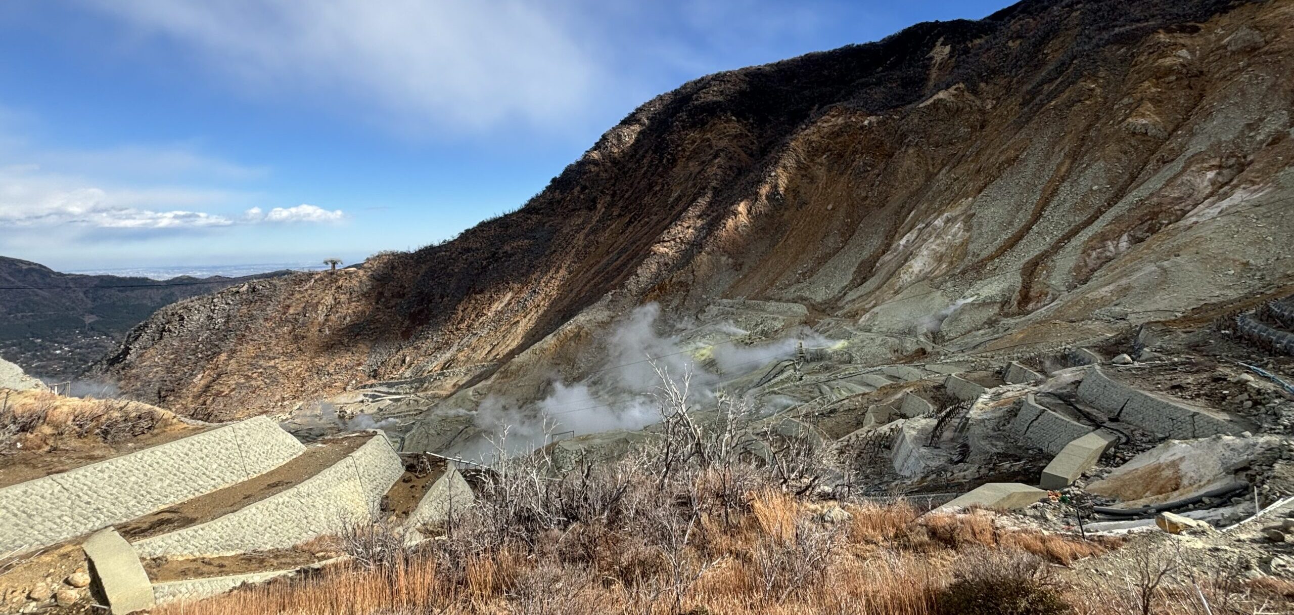 Volcanic landscape of Owakudani with steam vents and sulfurous fumes rising from the rocky terrain