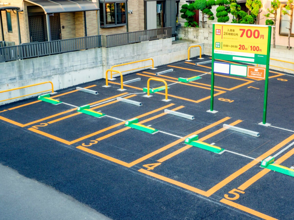 Outdoor coin parking lot with numbered spaces and parking rates sign