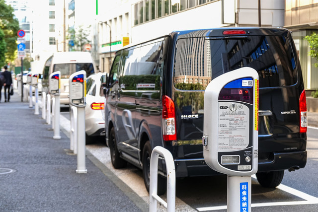 Row of street parking meters with parked vans in urban setting