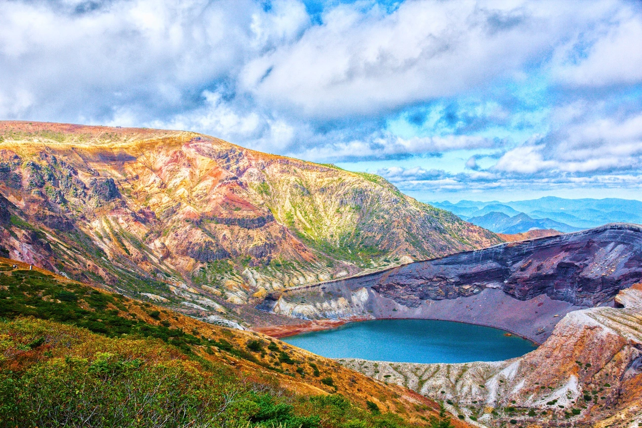 Blue water in Zao's Okama crater lake surrounded by volcanic slopes